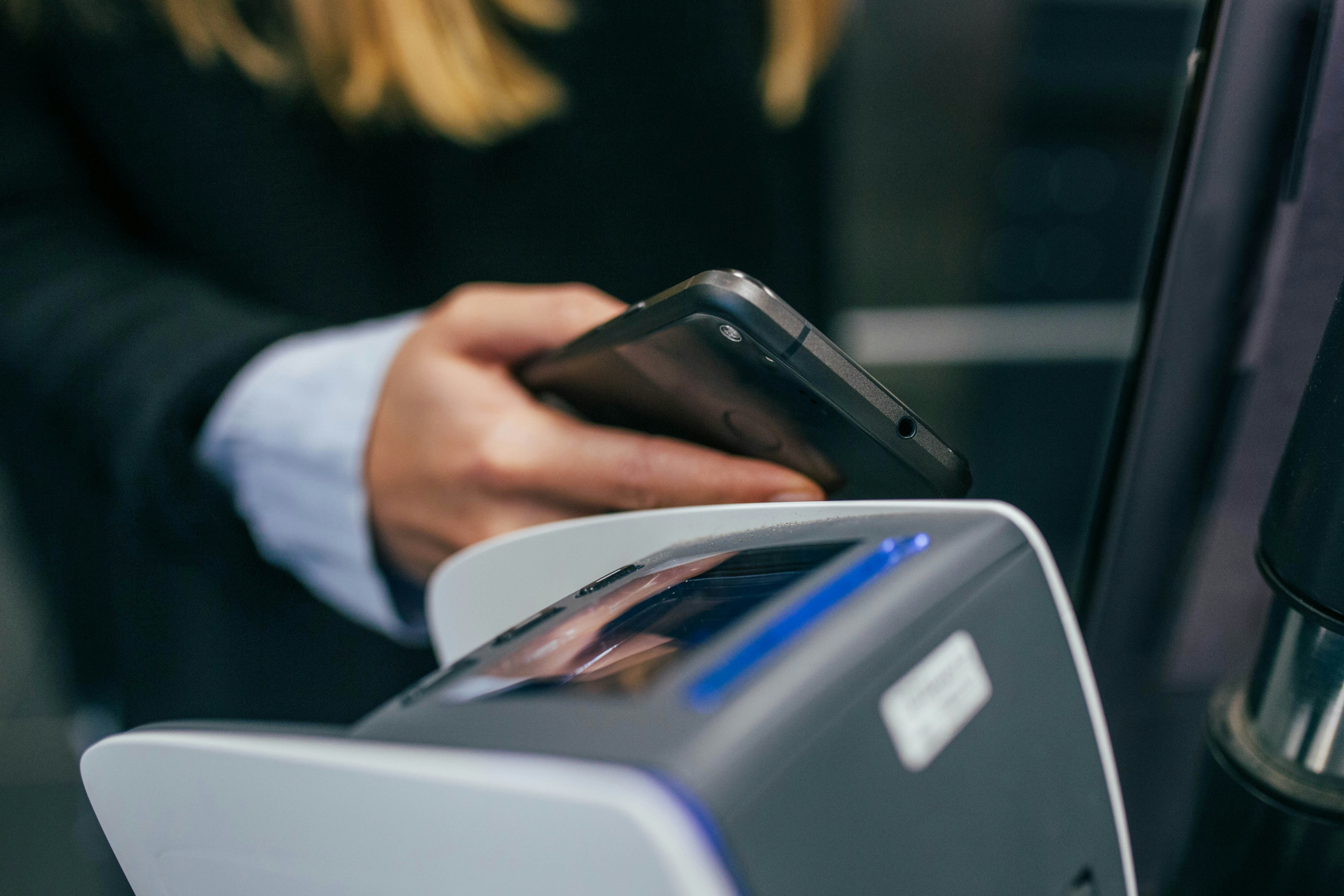 Homem com terno segurando celular do lado de um leitor de código