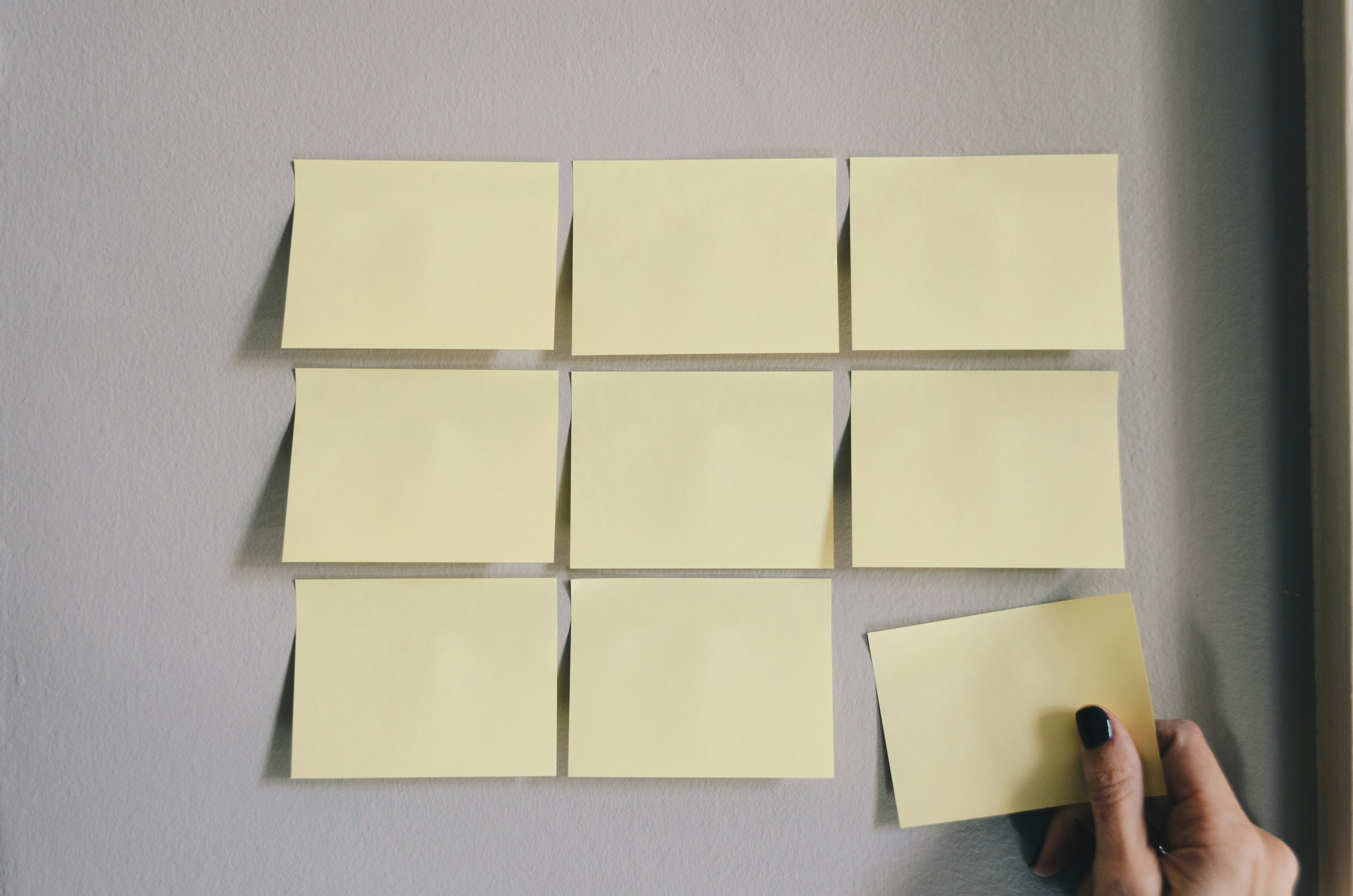 Quadro com post its. M&atilde;o branca colando post-it na pared