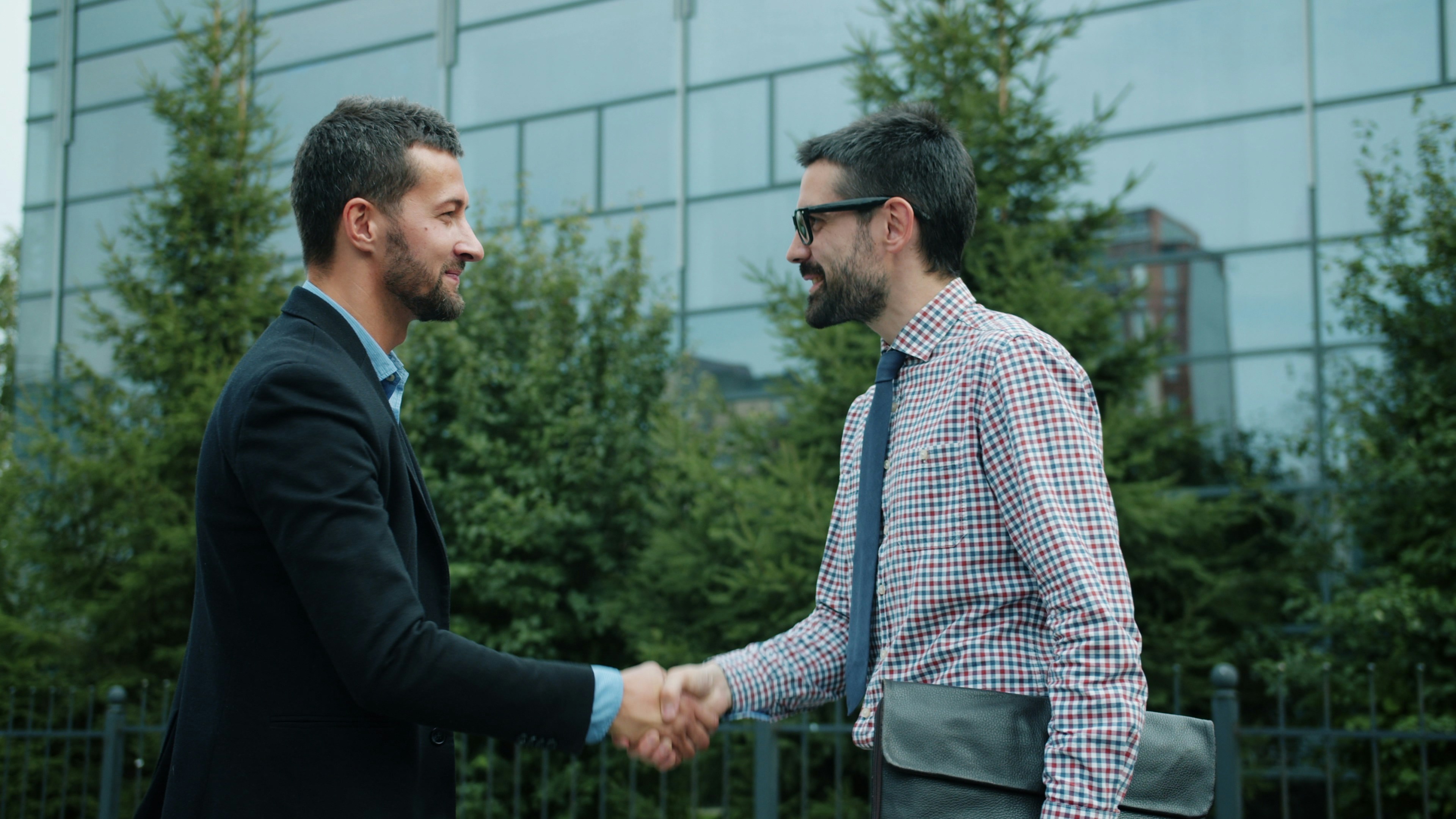 Aperto de mão entre empresários na frente de um prédio