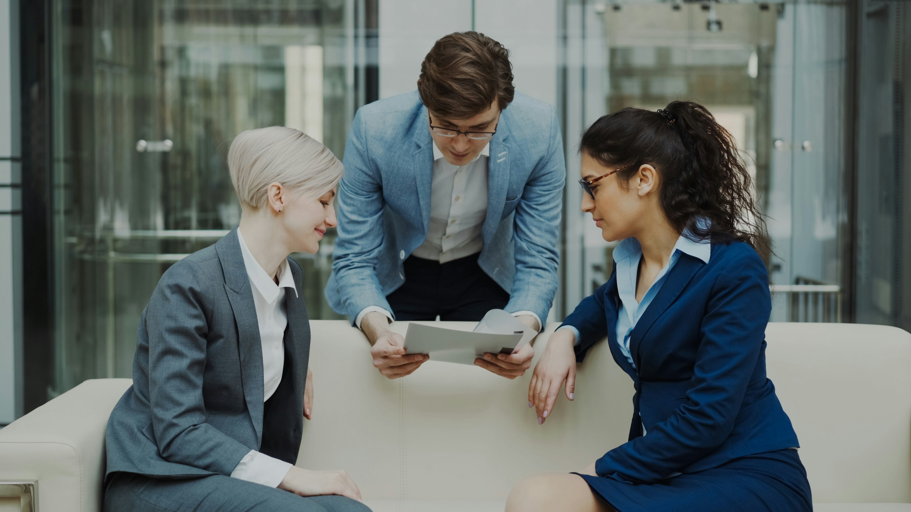 3 executivos vestindo roupas com tom azul olhando para um contrato